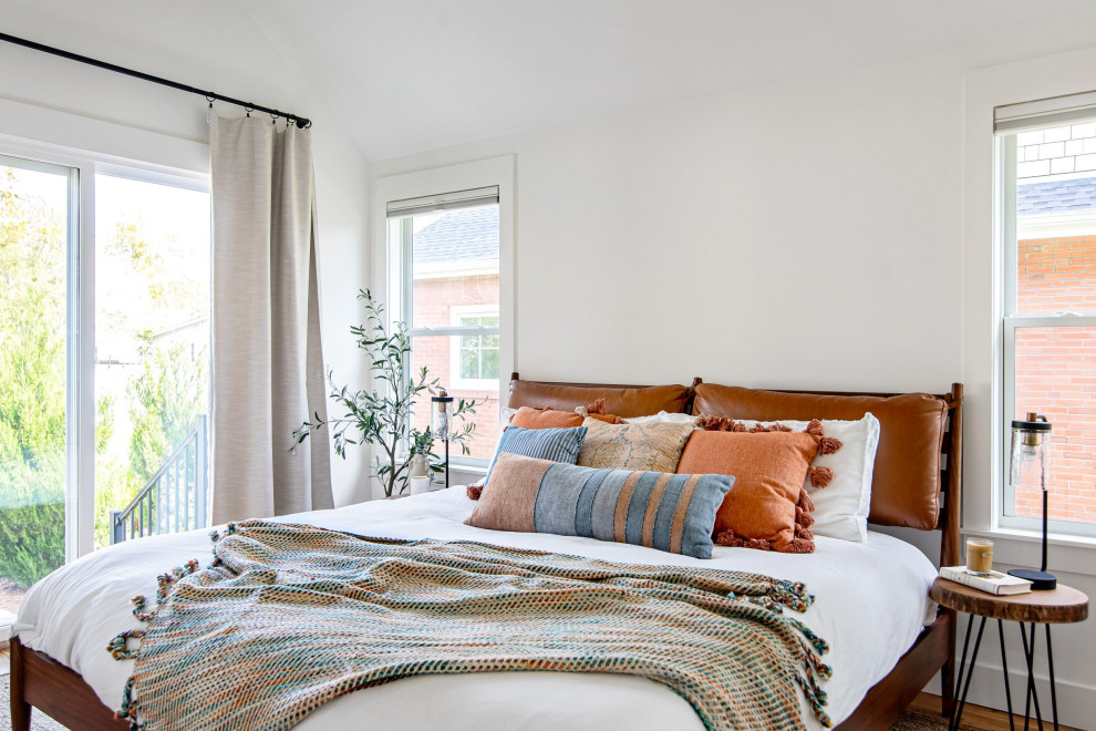 Idée de décoration pour une petite chambre parentale minimaliste avec un mur blanc, parquet clair et un plafond voûté.