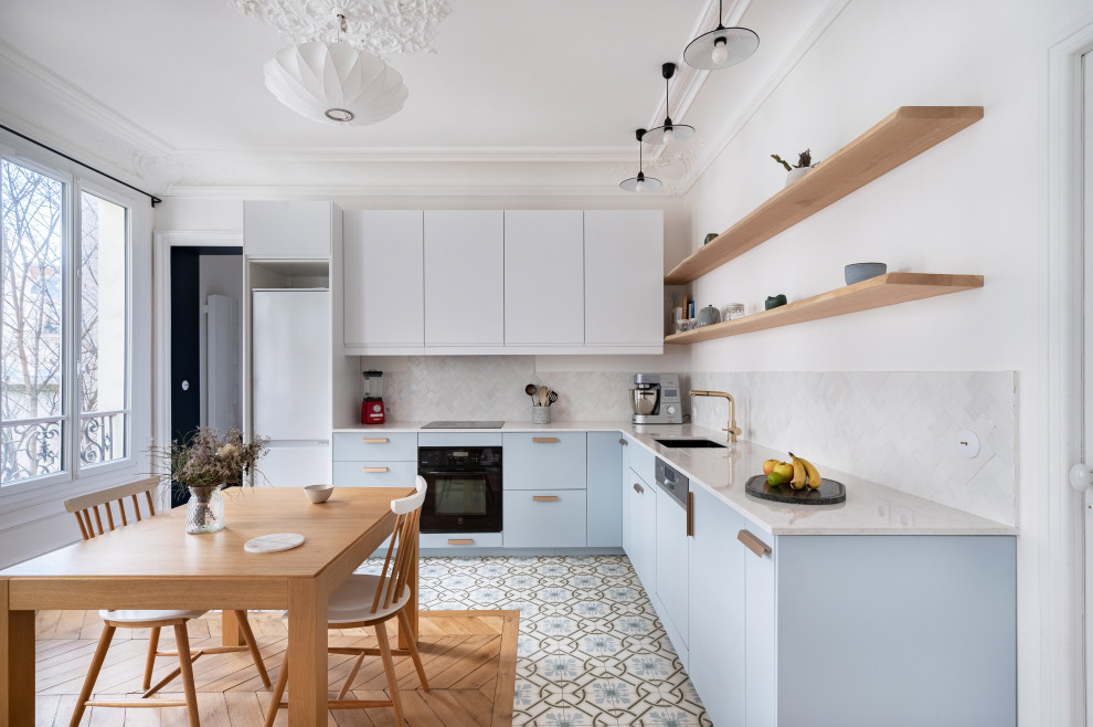 This is an example of a large contemporary l-shaped open plan kitchen in Paris with an undermount sink, quartzite benchtops, white splashback, ceramic splashback, cement tiles and white benchtop.