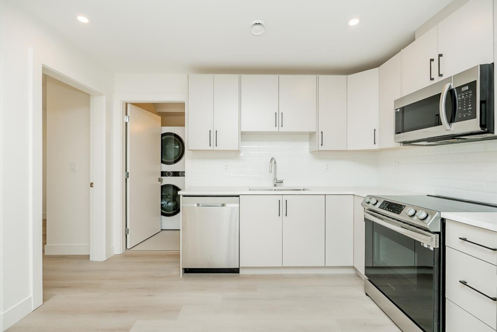 Small l-shaped vinyl floor and beige floor eat-in kitchen photo in Vancouver with an undermount sink, flat-panel cabinets, white cabinets, quartzite countertops, white backsplash, ceramic backsplash, stainless steel appliances, no island and white countertops
