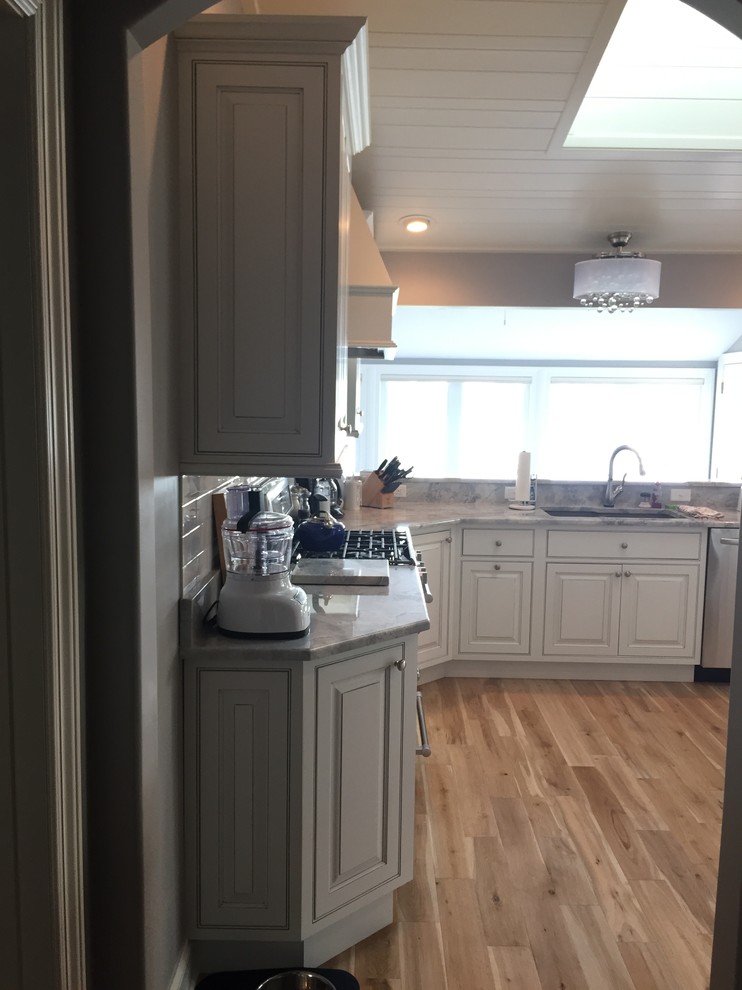 Open concept kitchen - large transitional u-shaped light wood floor open concept kitchen idea with an undermount sink, beaded inset cabinets, white cabinets, white appliances and a peninsula