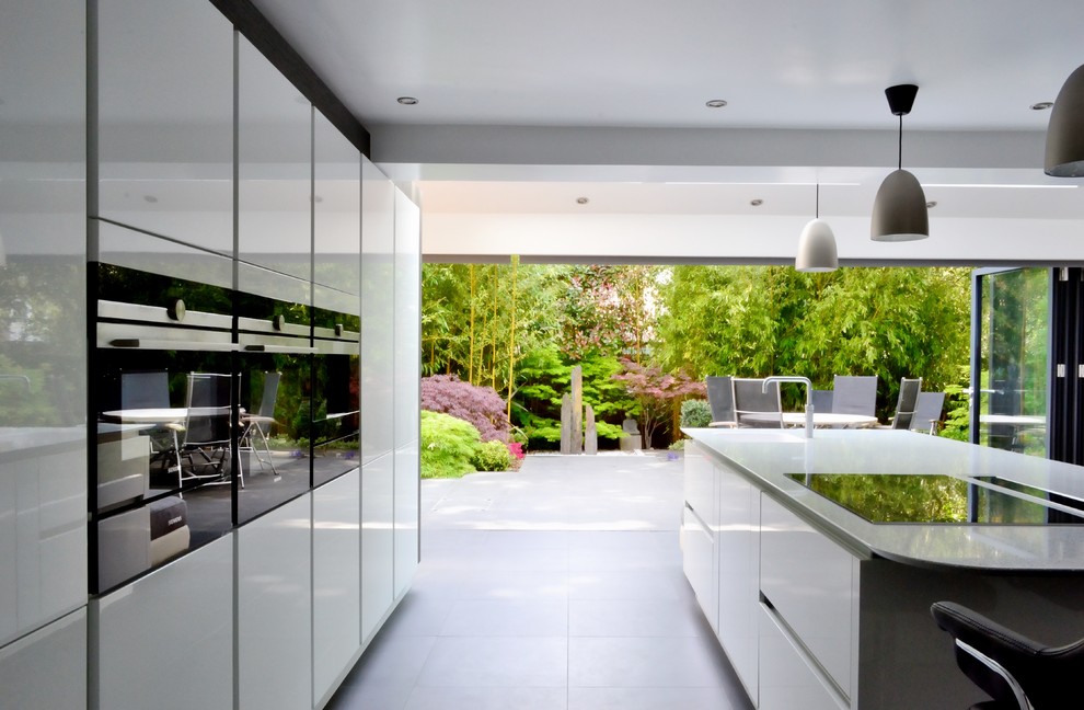 Contemporary single-wall kitchen in West Midlands with white cabinets, quartzite benchtops, porcelain floors and with island.