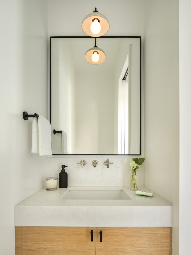Réalisation d'un petit WC suspendu minimaliste en bois clair avec un placard à porte plane, un mur blanc, un sol en bois brun, un lavabo encastré, un plan de toilette en quartz modifié, un plan de toilette blanc et meuble-lavabo suspendu.