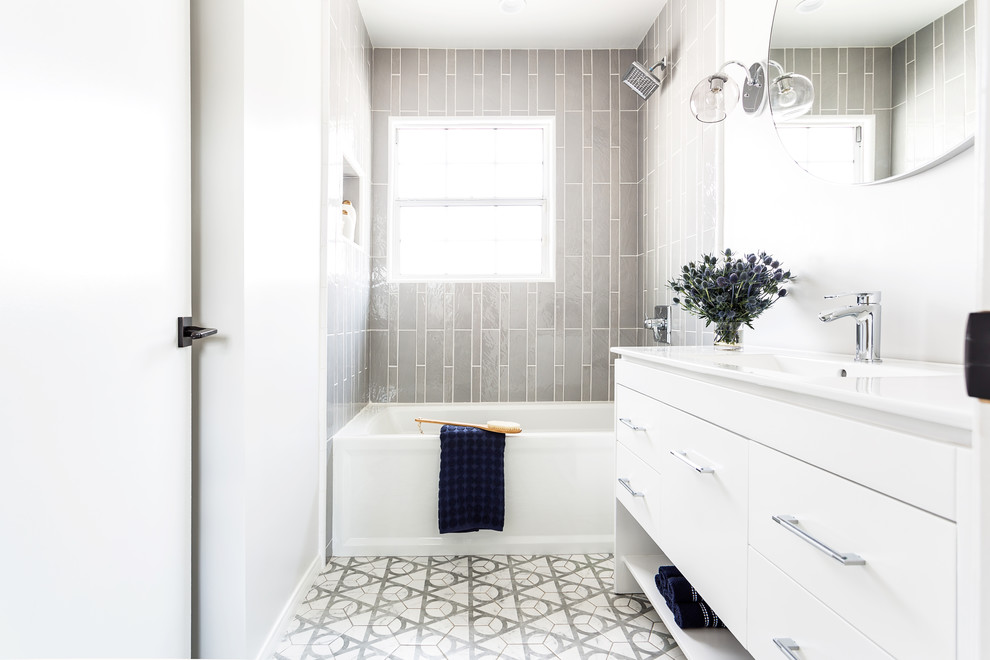 Mid-sized contemporary kids bathroom in Los Angeles with flat-panel cabinets, white cabinets, an alcove tub, a shower/bathtub combo, a one-piece toilet, gray tile, ceramic tile, white walls, ceramic floors, an integrated sink, engineered quartz benchtops, grey floor, a shower curtain and white benchtops.