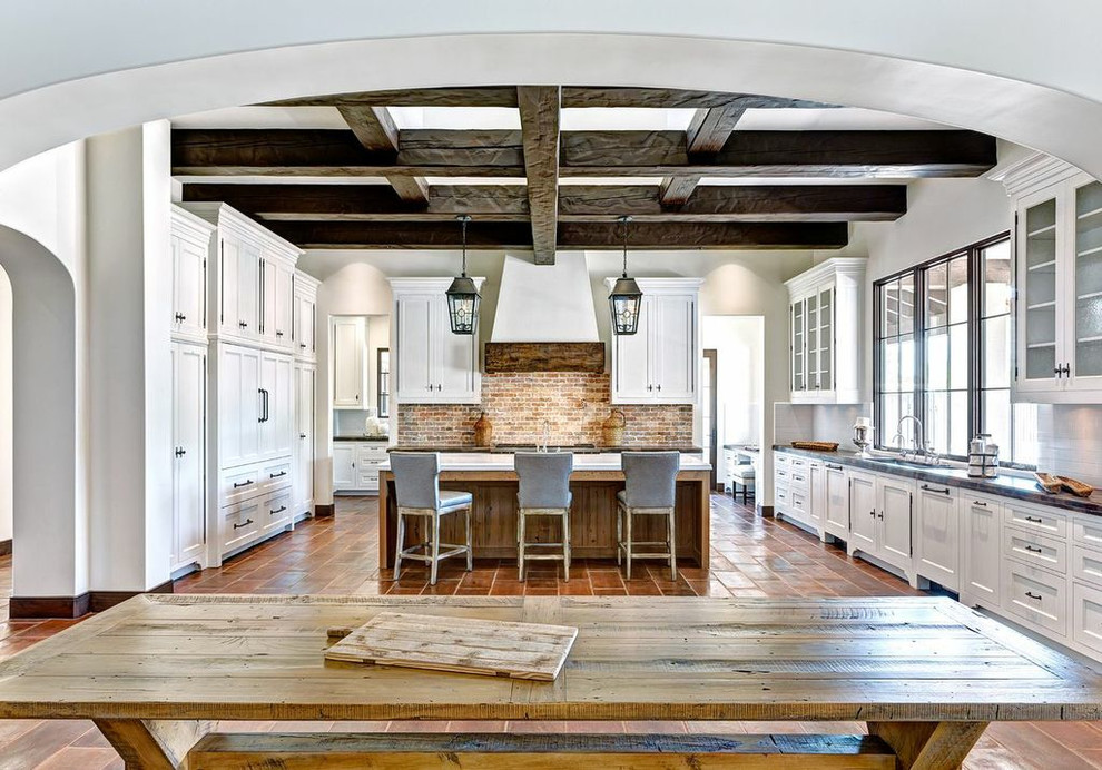 Mediterranean u-shaped eat-in kitchen in Phoenix with white cabinets and panelled appliances.