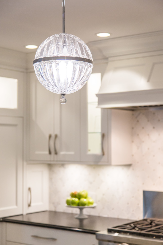 Large transitional l-shaped medium tone wood floor and beige floor eat-in kitchen photo in Vancouver with an undermount sink, shaker cabinets, white cabinets, granite countertops, gray backsplash, marble backsplash, stainless steel appliances, an island and black countertops