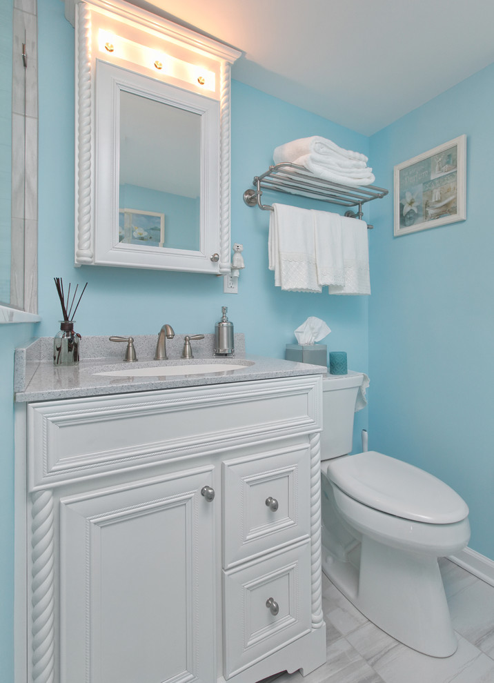 This is an example of a mid-sized beach style 3/4 bathroom in Philadelphia with furniture-like cabinets, white cabinets, a corner shower, a two-piece toilet, multi-coloured tile, ceramic tile, blue walls, ceramic floors, an undermount sink and glass benchtops.