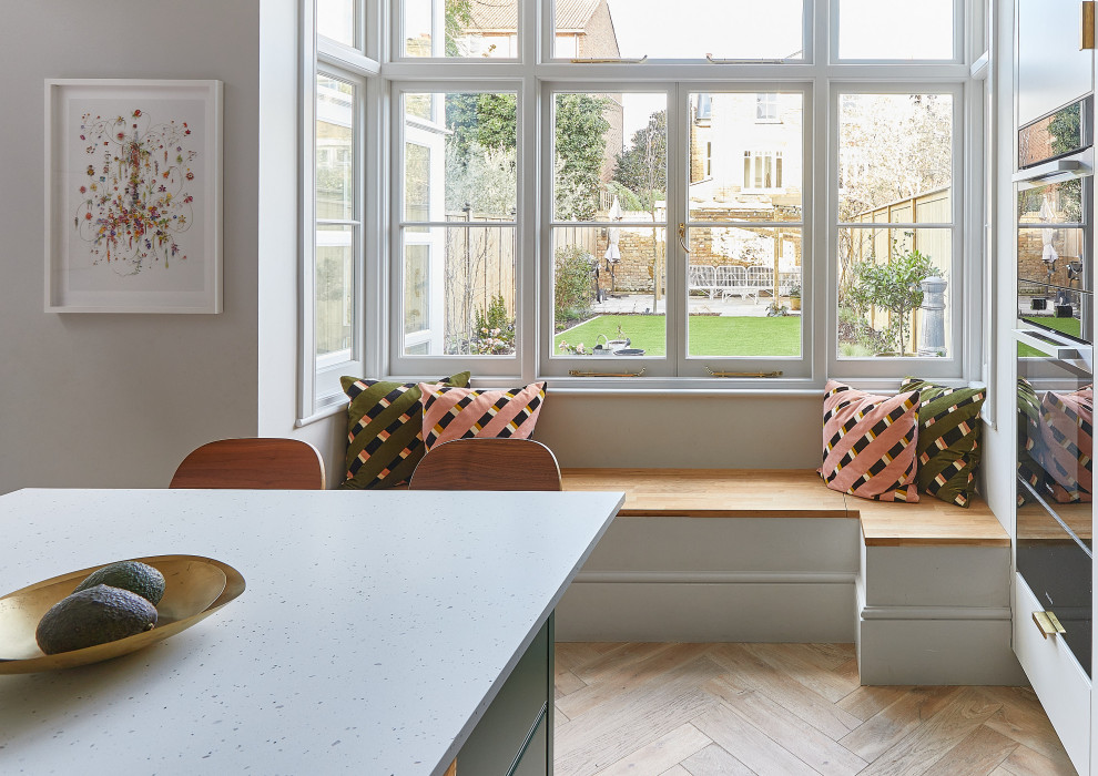 Photo of a large scandinavian galley eat-in kitchen in London with an undermount sink, flat-panel cabinets, green cabinets, quartzite benchtops, metallic splashback, metal splashback, panelled appliances, light hardwood floors, with island, beige floor, white benchtop and wood.