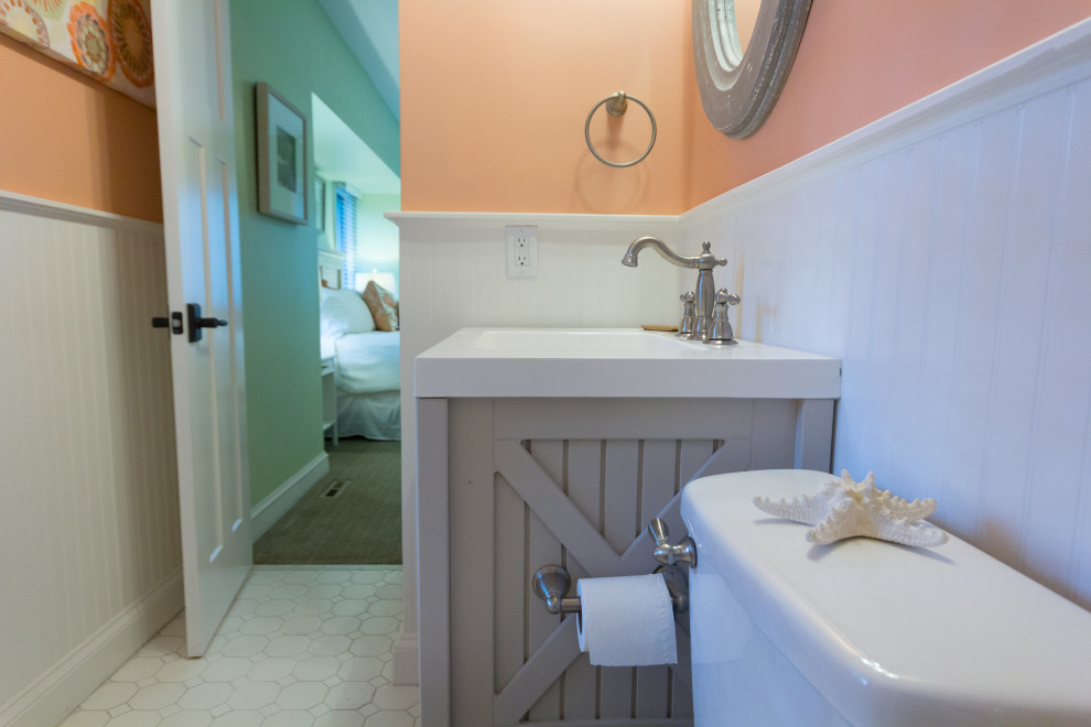 This is an example of a small beach style bathroom in Atlanta with grey cabinets, an alcove tub, an alcove shower, a two-piece toilet, white tile, porcelain tile, pink walls, medium hardwood floors, an undermount sink, solid surface benchtops, white floor, white benchtops, a single vanity and a freestanding vanity.