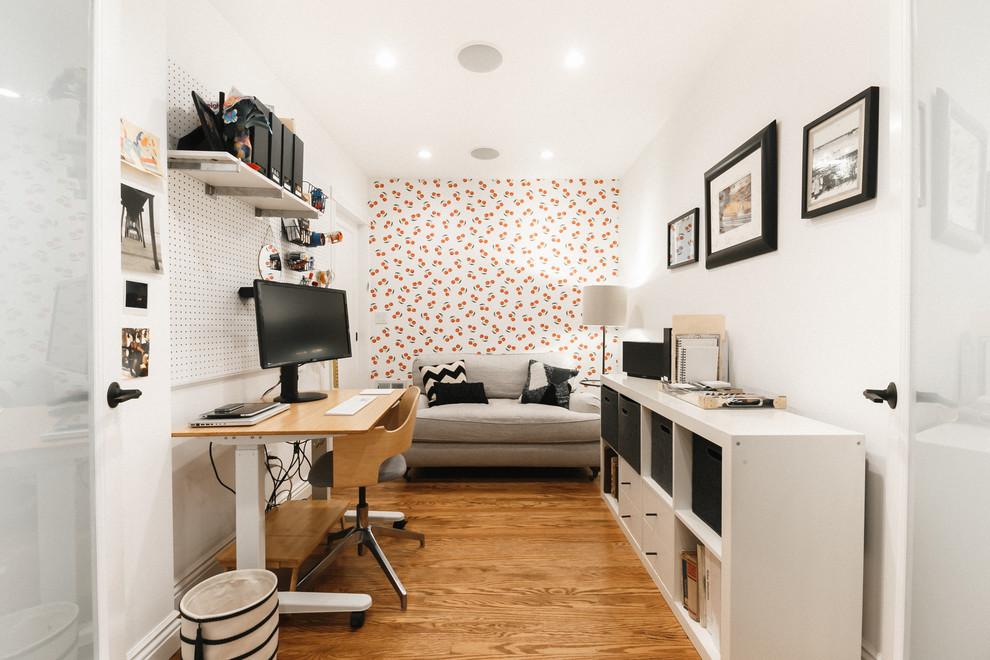 Trendy freestanding desk medium tone wood floor and brown floor home office photo in San Francisco with white walls