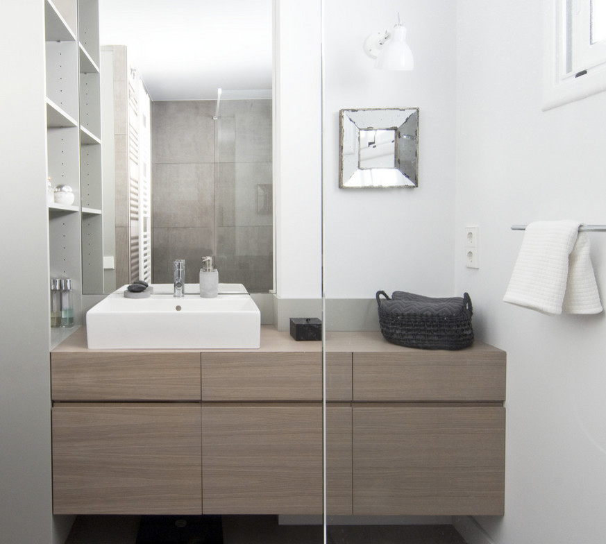 Diseño de aseo moderno con puertas de armario de madera oscura, paredes blancas y lavabo sobreencimera