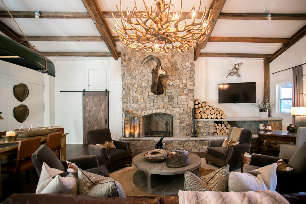 Inspiration for a country open concept living room in Charleston with white walls, dark hardwood floors, a standard fireplace, a stone fireplace surround, a wall-mounted tv and brown floor.