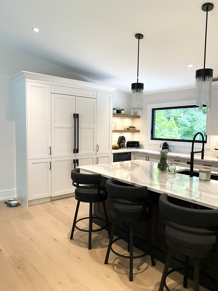 Example of a large transitional l-shaped light wood floor and vaulted ceiling open concept kitchen design in Toronto with an undermount sink, recessed-panel cabinets, white cabinets, quartz countertops, white backsplash, porcelain backsplash, stainless steel appliances, an island and white countertops
