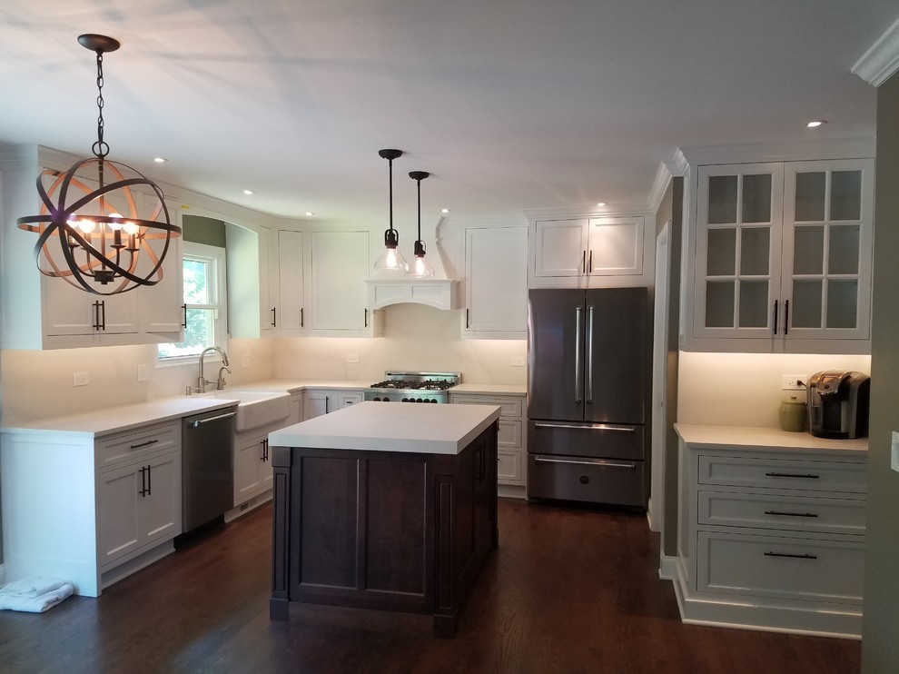 Eat-in kitchen - mid-sized transitional l-shaped medium tone wood floor and brown floor eat-in kitchen idea in Chicago with a farmhouse sink, recessed-panel cabinets, white cabinets, quartz countertops, white backsplash, stainless steel appliances and an island