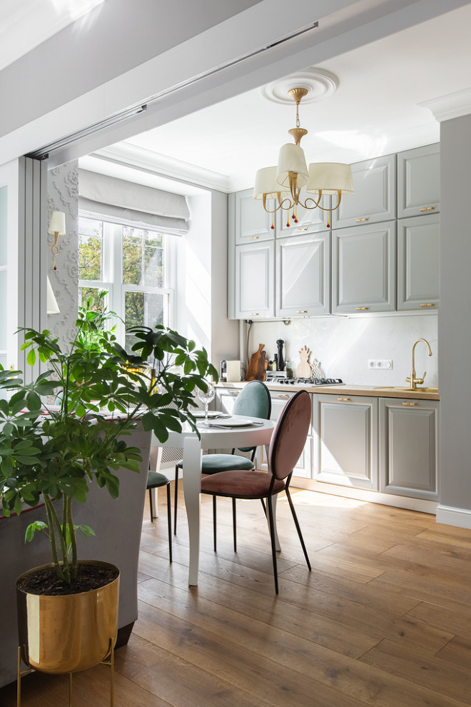 Design ideas for a mid-sized transitional single-wall eat-in kitchen with an undermount sink, recessed-panel cabinets, grey cabinets, wood benchtops, white splashback, porcelain splashback, stainless steel appliances, medium hardwood floors, no island and beige benchtop.