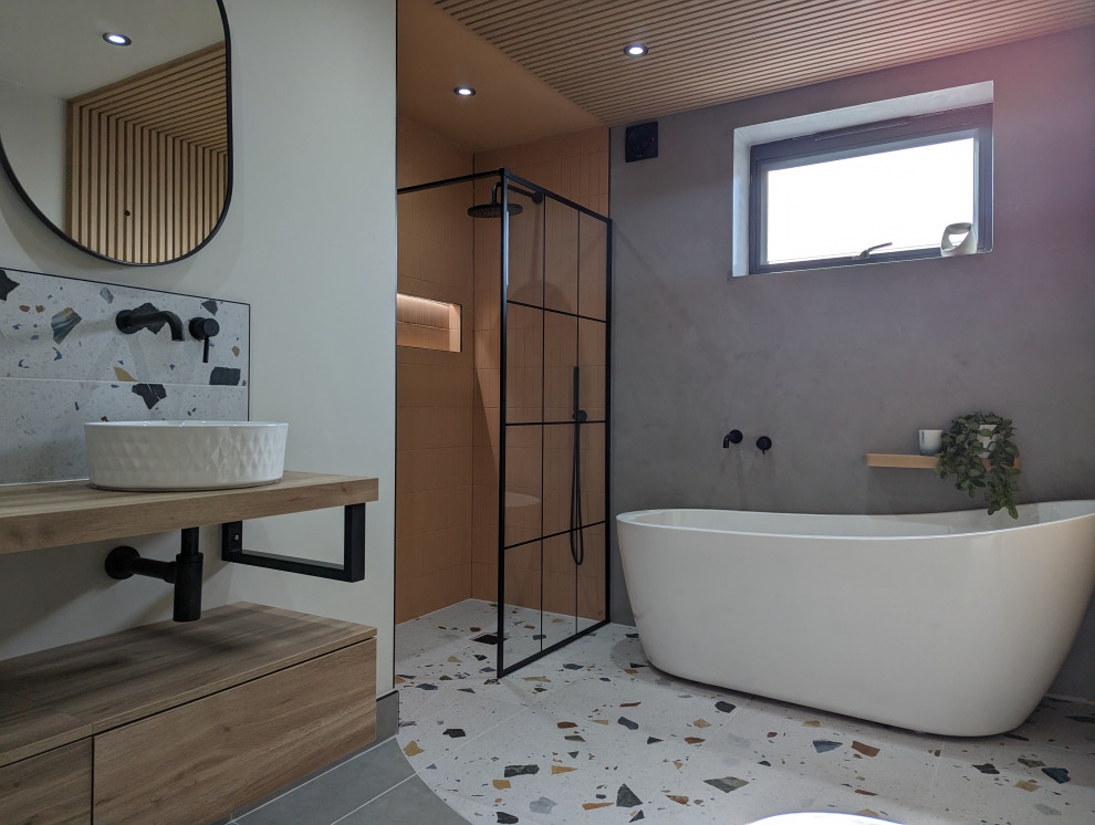 Photo of a large contemporary kids bathroom in Other with flat-panel cabinets, light wood cabinets, a freestanding tub, an open shower, a one-piece toilet, green walls, ceramic floors, an integrated sink, wood benchtops, multi-coloured floor, an open shower, a double vanity, a freestanding vanity and panelled walls.