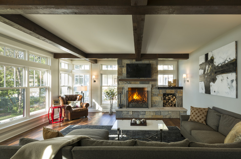 This is an example of a transitional open concept living room in Minneapolis with grey walls, dark hardwood floors, a standard fireplace, a wall-mounted tv and a stone fireplace surround.