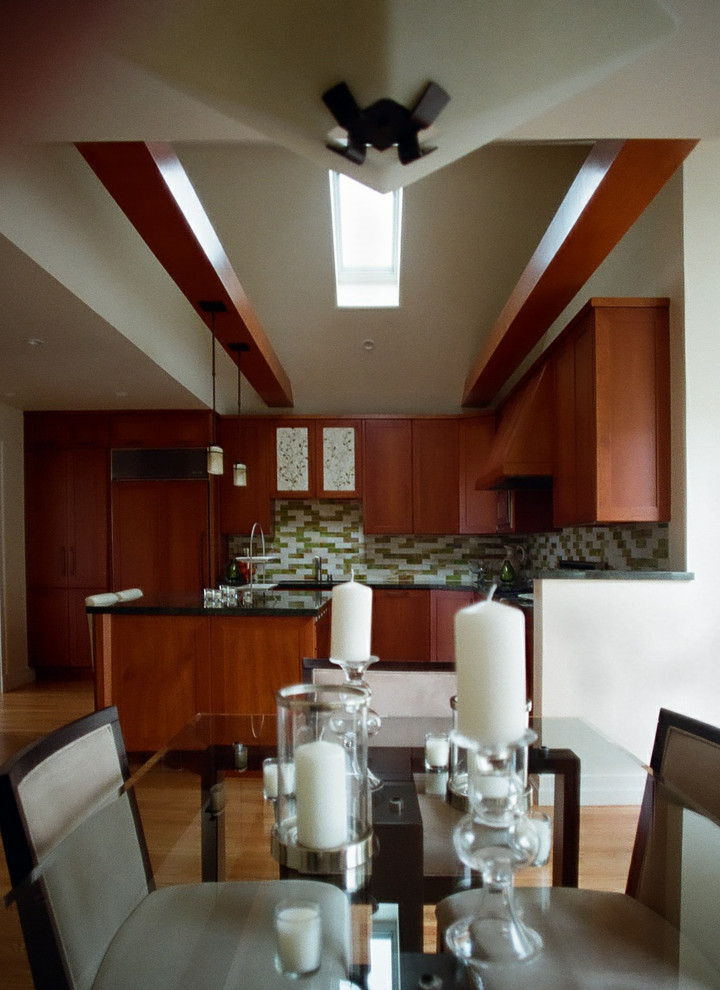This is an example of a mid-sized arts and crafts l-shaped open plan kitchen in San Francisco with an undermount sink, shaker cabinets, brown cabinets, granite benchtops, green splashback, glass tile splashback, panelled appliances, medium hardwood floors, with island, beige floor, green benchtop and vaulted.