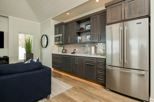 Compact studio kitchen with dark-stained shaker kitchen cabinet run, open shelf niches, under-cabinet lighting, subway tile backsplash, and a stainless French-door fridge