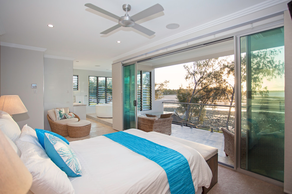 This is an example of a mid-sized beach style master bedroom in Other with white walls, carpet and brown floor.