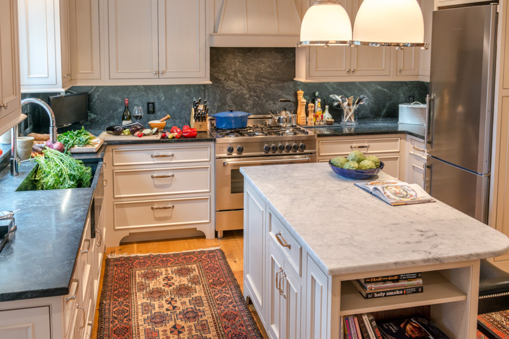 This is an example of a mid-sized arts and crafts u-shaped kitchen in Boston with an undermount sink, beaded inset cabinets, beige cabinets, quartz benchtops, blue splashback, stone slab splashback, stainless steel appliances, light hardwood floors, with island and brown floor.