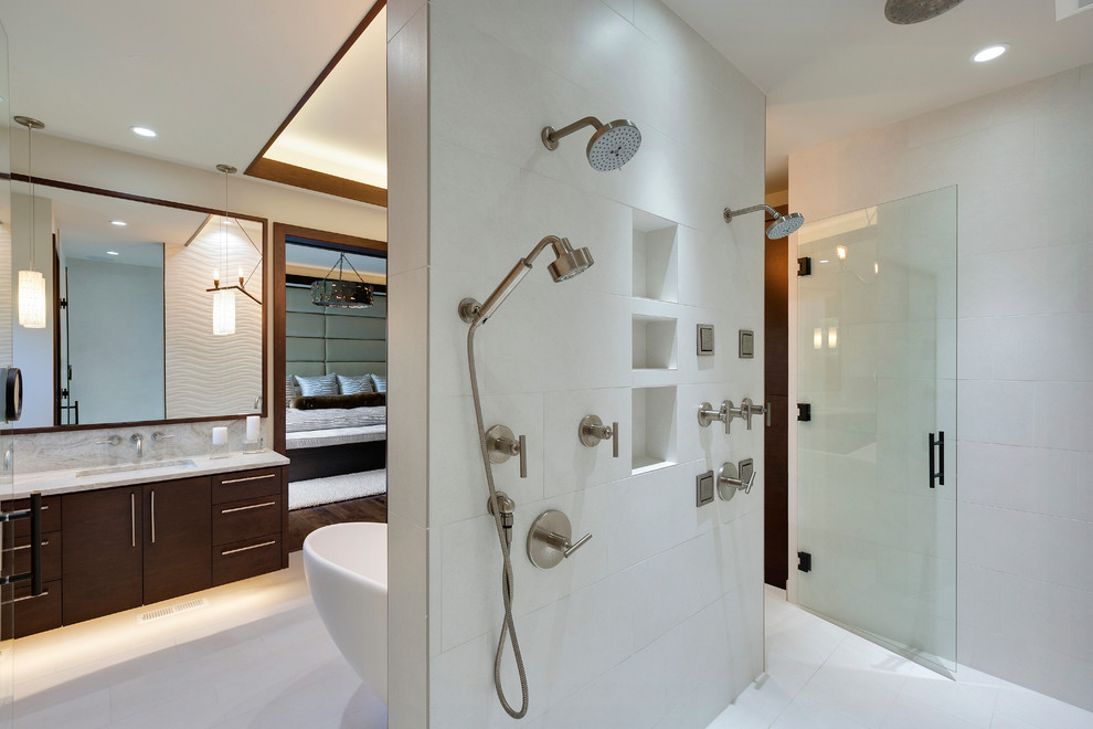 This is an example of a large contemporary master wet room bathroom in Minneapolis with flat-panel cabinets, medium wood cabinets, a freestanding tub, a two-piece toilet, white tile, porcelain tile, white walls, porcelain floors, an undermount sink, marble benchtops, white floor and an open shower.
