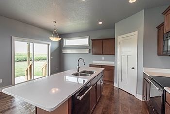 Example of a mid-sized transitional l-shaped medium tone wood floor eat-in kitchen design with an undermount sink, recessed-panel cabinets, medium tone wood cabinets, quartz countertops, black appliances and an island