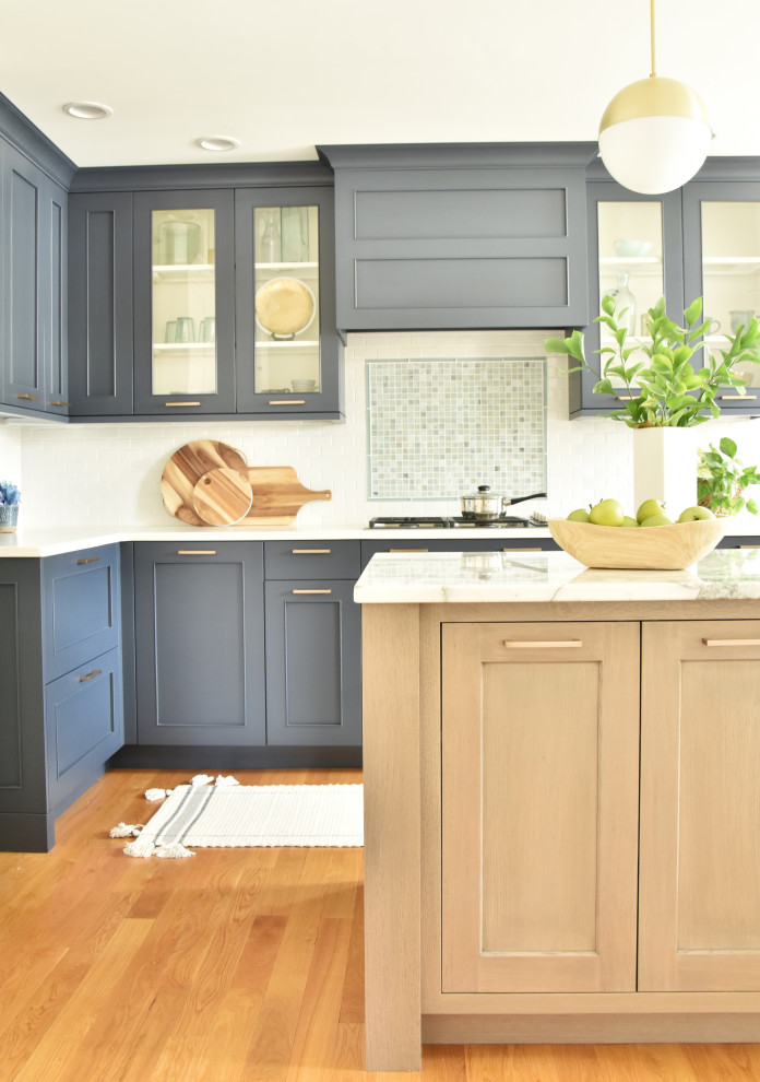 Klassisk inredning av ett avskilt, mellanstort vit vitt l-kök, med släta luckor, blå skåp, marmorbänkskiva, blått stänkskydd, stänkskydd i glaskakel, mellanmörkt trägolv och en köksö