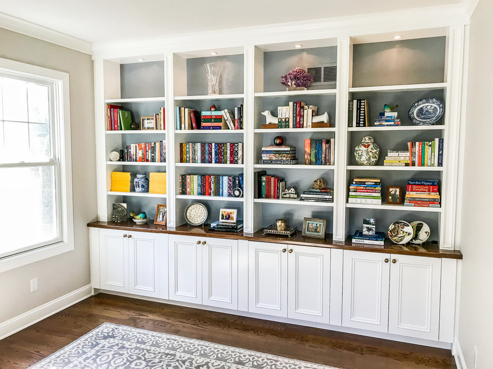 This is an example of a mid-sized transitional enclosed living room in New York with a library, beige walls, dark hardwood floors and brown floor.