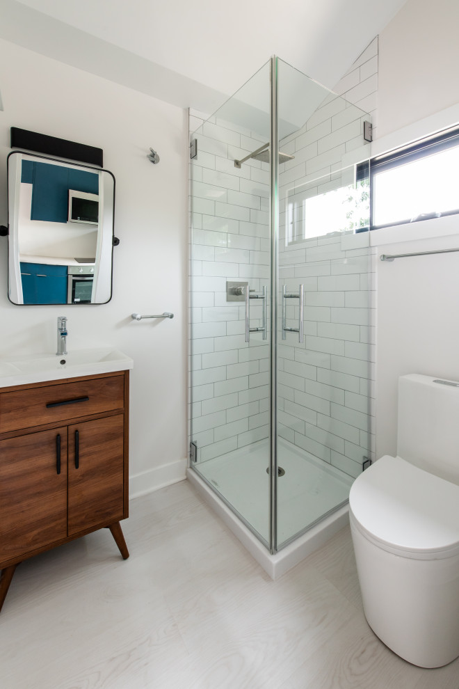 Inspiration for a small contemporary 3/4 bathroom in DC Metro with furniture-like cabinets, medium wood cabinets, a corner shower, a one-piece toilet, white tile, subway tile, white walls, linoleum floors, a console sink, grey floor, a hinged shower door, a laundry, a single vanity and a built-in vanity.