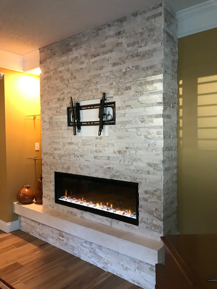 Example of a mid-sized transitional medium tone wood floor living room design in Tampa with beige walls, a ribbon fireplace, a stone fireplace and a wall-mounted tv