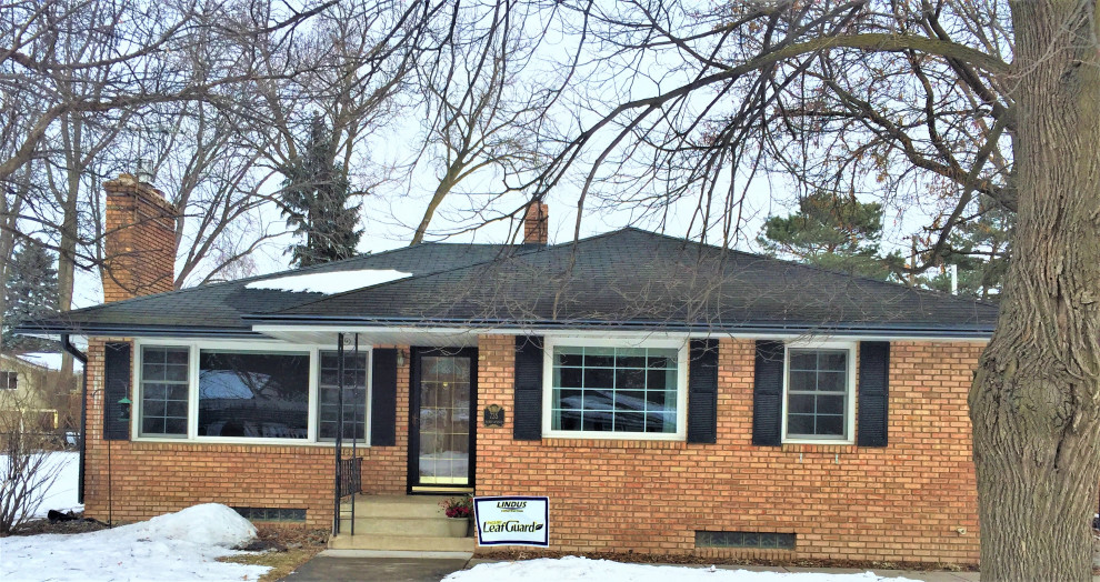 Photo of a mid-sized midcentury one-storey brick orange house exterior in Minneapolis with a black roof.