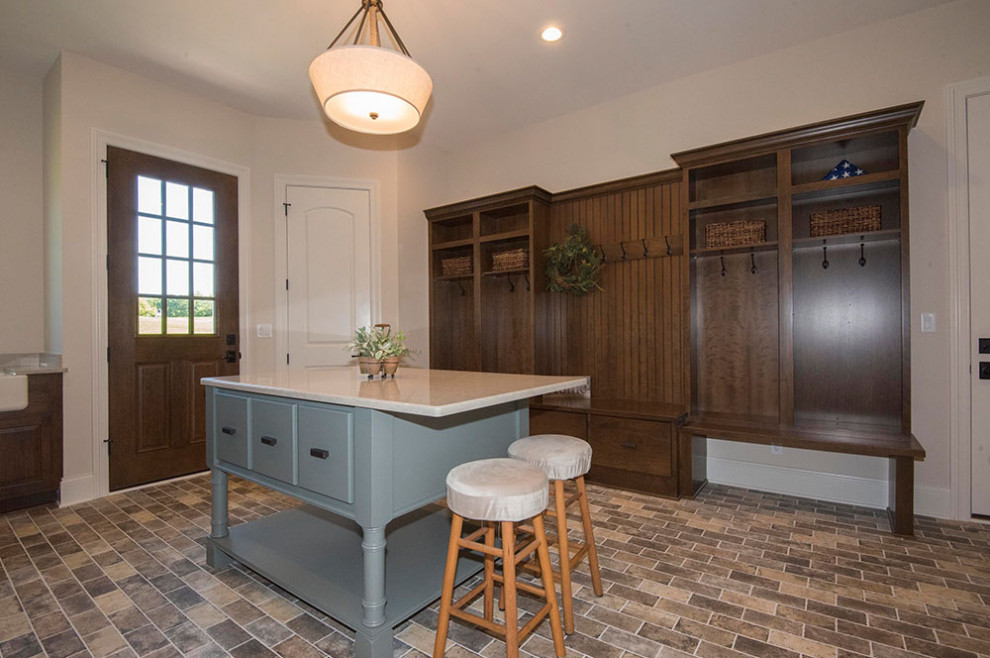 Inspiration for a large transitional utility room in Milwaukee with a farmhouse sink, raised-panel cabinets, medium wood cabinets, quartz benchtops, beige walls, brick floors, a side-by-side washer and dryer, beige floor and beige benchtop.