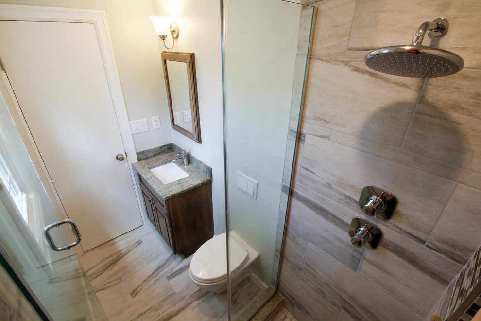 Photo of a small transitional master bathroom in Newark with raised-panel cabinets, medium wood cabinets, an alcove shower, a wall-mount toilet, multi-coloured tile, porcelain tile, green walls, porcelain floors, an undermount sink, granite benchtops, beige floor and a hinged shower door.
