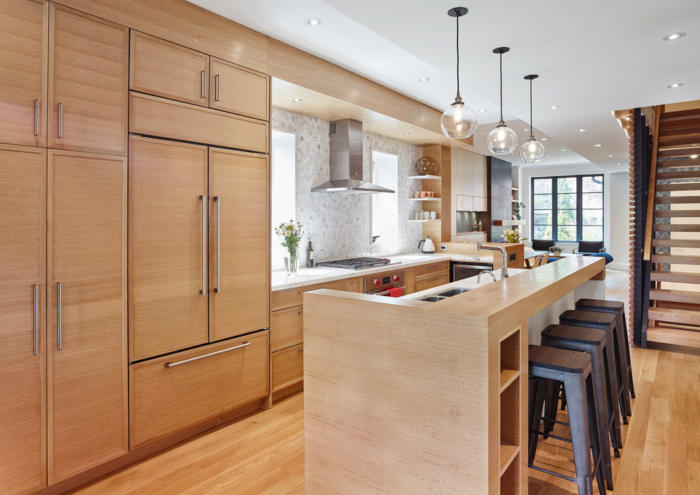 Design ideas for a contemporary galley kitchen in Toronto with a double-bowl sink, flat-panel cabinets, light wood cabinets, marble splashback, stainless steel appliances, light hardwood floors and with island.