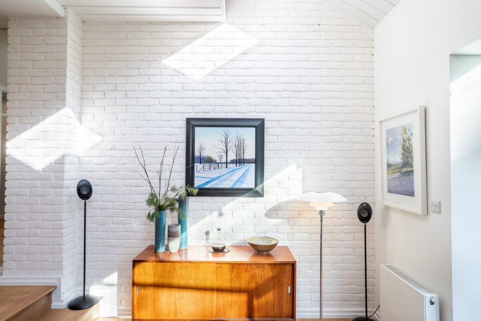 Offenes Skandinavisches Wohnzimmer mit weißer Wandfarbe, braunem Holzboden, Kaminofen, Holzdielendecke und Ziegelwänden in London