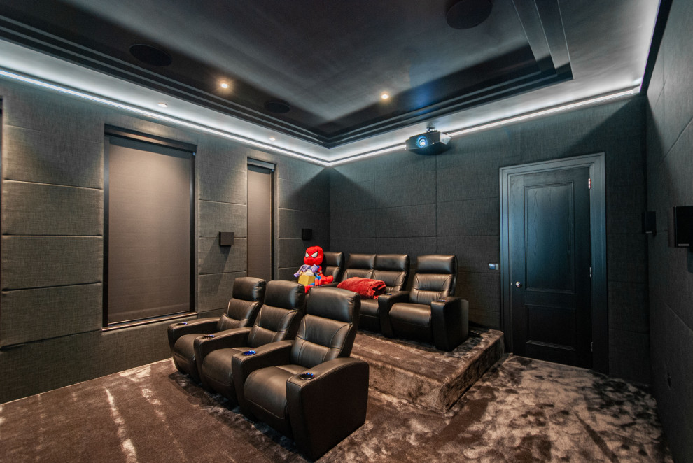 Inspiration for a large modern enclosed home theatre in Surrey with black walls, carpet, a projector screen and grey floor.