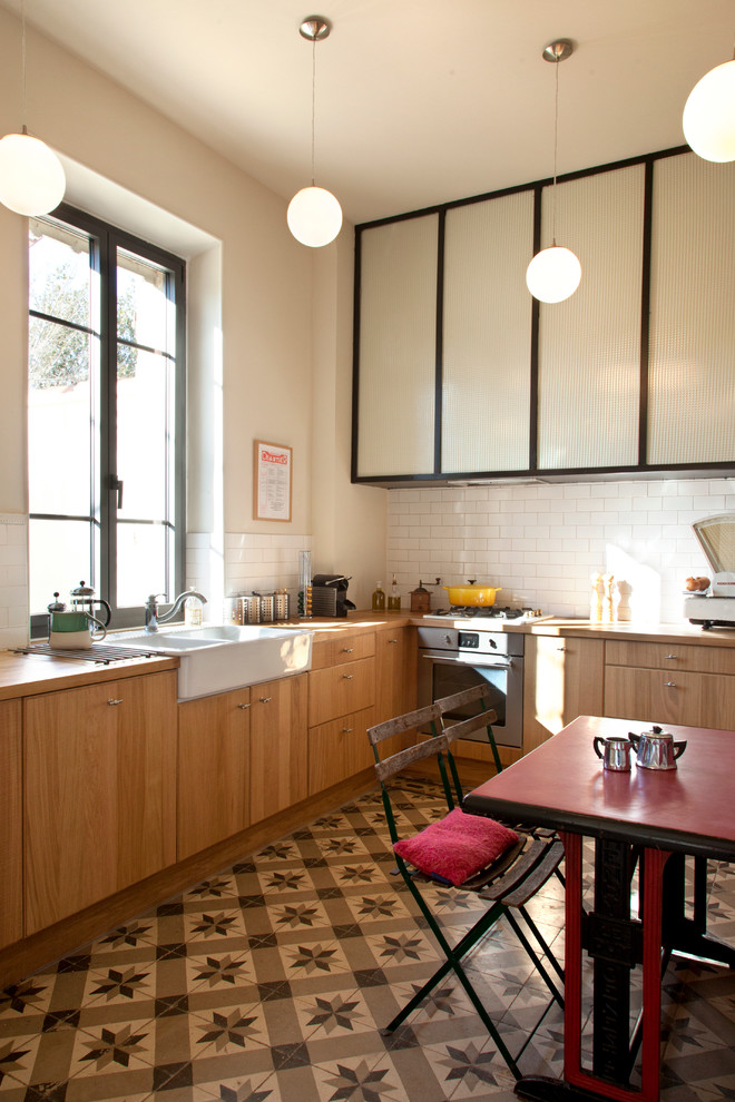 Photo of a large eclectic l-shaped eat-in kitchen in Marseille with a farmhouse sink, white splashback, subway tile splashback, ceramic floors, no island and medium wood cabinets.