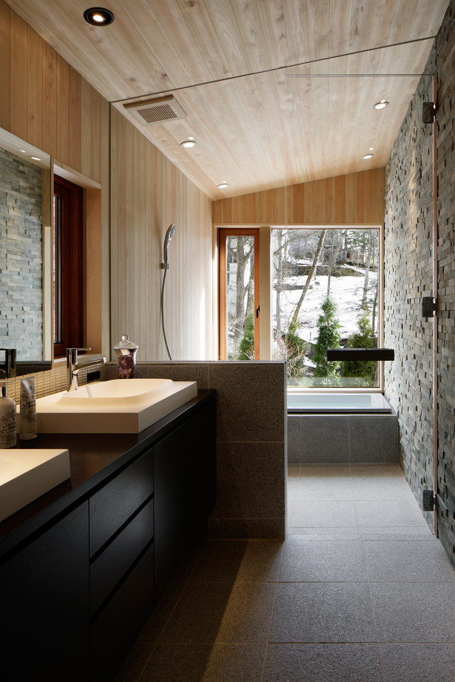 Contemporary bathroom in Other with flat-panel cabinets, dark wood cabinets, a corner tub, an open shower, multi-coloured walls, a vessel sink, grey floor and an open shower.