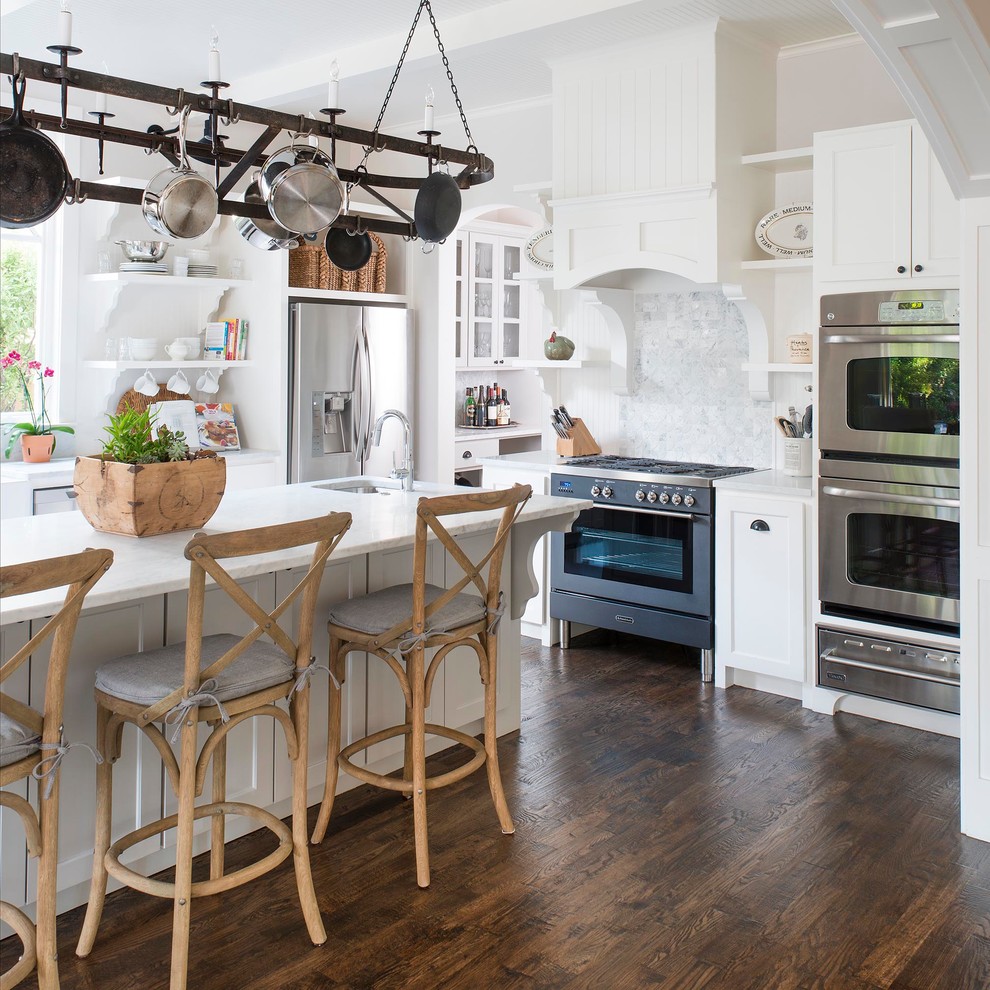 Design ideas for a traditional l-shaped kitchen in Dallas with an undermount sink, shaker cabinets, white cabinets, multi-coloured splashback, stainless steel appliances, dark hardwood floors, with island and brown floor.