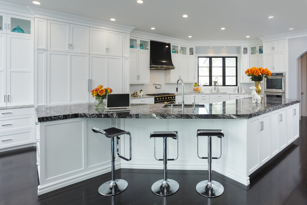 Inspiration for a transitional l-shaped dark wood floor kitchen remodel with an undermount sink, shaker cabinets, an island, white backsplash and gray countertops