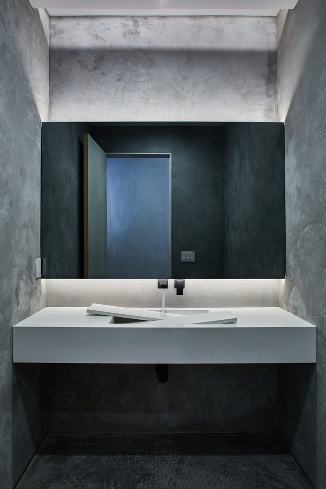 This is an example of a modern powder room in Los Angeles with grey walls, grey floor and white benchtops.