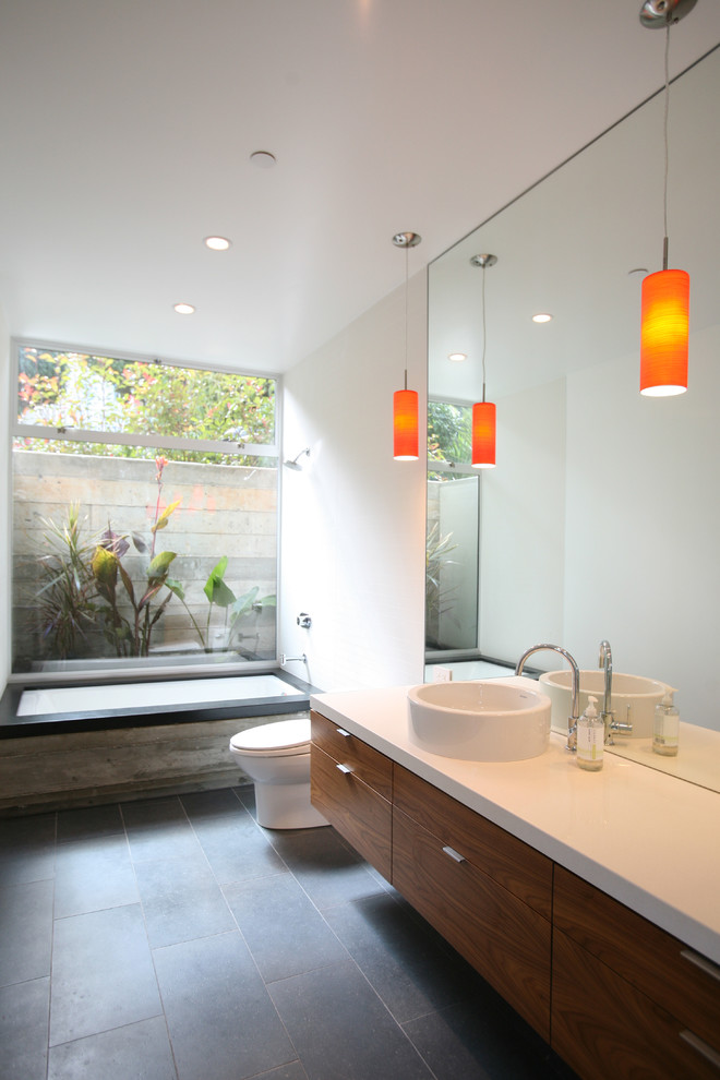 Photo of a modern bathroom in San Francisco with a vessel sink, flat-panel cabinets, an undermount tub, a shower/bathtub combo, white walls and medium wood cabinets.