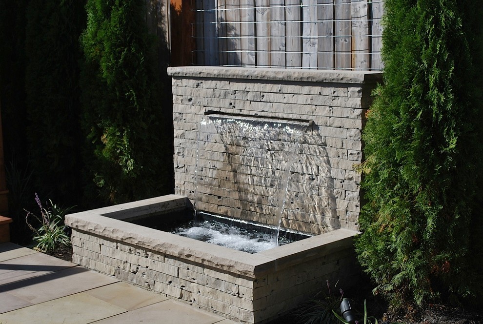 Small traditional backyard full sun garden in Toronto with a water feature and concrete pavers for spring.