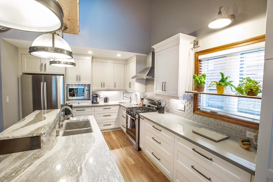 Inspiration for a mid-sized transitional l-shaped medium tone wood floor and brown floor eat-in kitchen remodel with an undermount sink, shaker cabinets, white cabinets, quartzite countertops, white backsplash, subway tile backsplash, paneled appliances and an island