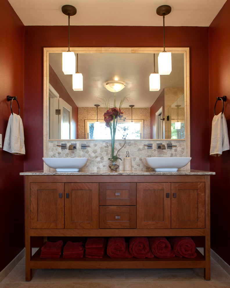 This is an example of a mid-sized arts and crafts master bathroom in San Francisco with a vessel sink, recessed-panel cabinets, medium wood cabinets, marble benchtops, a freestanding tub, an alcove shower, a two-piece toilet, beige tile, ceramic tile, red walls and ceramic floors.