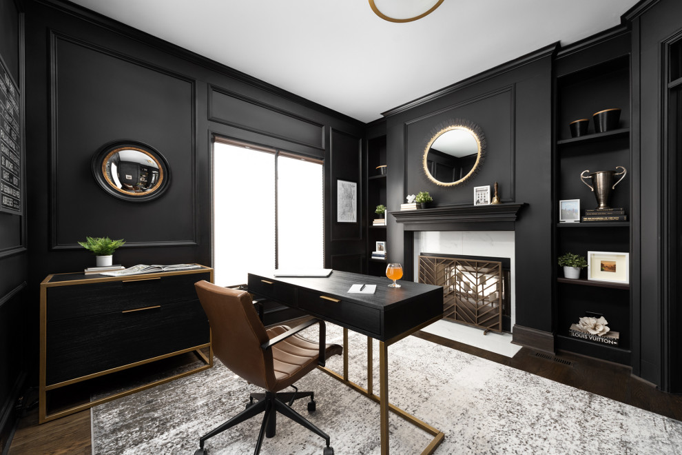 This is an example of a large transitional study room in Chicago with black walls, dark hardwood floors, a two-sided fireplace, a stone fireplace surround, a freestanding desk and decorative wall panelling.