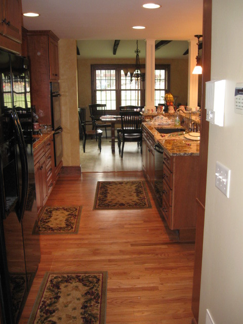 Large transitional l-shaped dark wood floor open concept kitchen photo in Providence with an undermount sink, glass-front cabinets, white cabinets, granite countertops, beige backsplash, subway tile backsplash, stainless steel appliances and an island