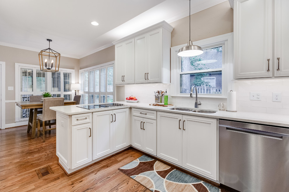 Example of a mid-sized transitional u-shaped medium tone wood floor and brown floor eat-in kitchen design in Birmingham with a double-bowl sink, recessed-panel cabinets, white cabinets, quartz countertops, white backsplash, subway tile backsplash, stainless steel appliances, a peninsula and white countertops