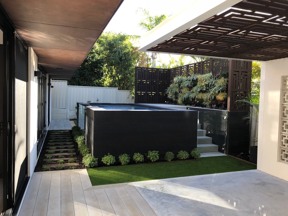 This is an example of a mid-sized industrial backyard rectangular aboveground pool in Perth with decking.