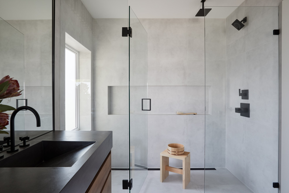 Modern bathroom in Vancouver with a curbless shower, gray tile, an integrated sink, grey floor, a hinged shower door, black benchtops and a niche.